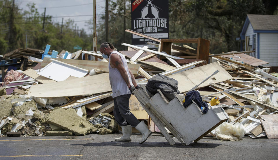 Joey Vene, a member of New Beginnings in Harvey, La., drags the baptismal stairs to the debris pile while helping gut the Lighthouse Church in Lafitte, La., Tuesday, Sept. 7, 2021, in the aftermath of Hurricane Ida. (David Grunfeld/The Times-Picayune/The New Orleans Advocate via AP)