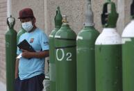 A man waits by his empty oxygen tank in a line of other customers outside a shop that refills them in the Villa El Salvador shantytown of Lima, Peru, Thursday, Jan. 21, 2021, amid the COVID-19 pandemic. (AP Photo/Martin Mejia)