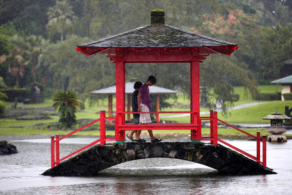 <p>Two men walk through a park flooded by rain from Hurricane Lane in Hilo, Hawaii, Aug. 25, 2018. (Photo: Terray Sylvester/Reuters) </p>