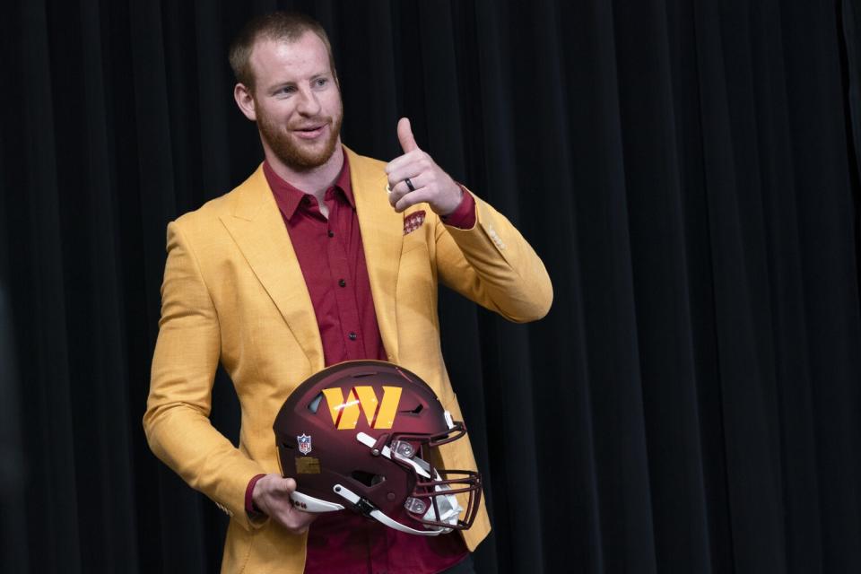 Washington Commanders quarterback Carson Wentz gives a thumbs up during his introductory news conference.