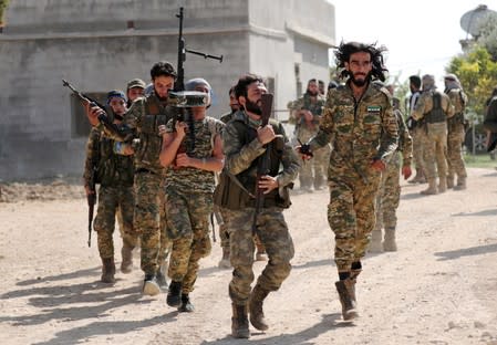 Turkey-backed Syrian rebel fighters walk together near the border town of Tel Abyad