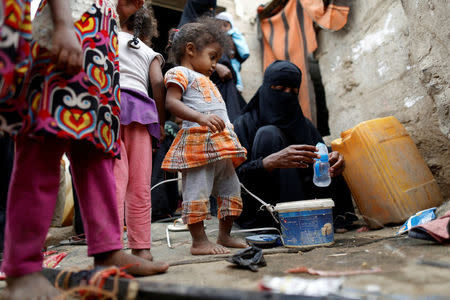 A girl displaced from the Red Sea port city of Hodeidah looks as her mother washes her milk bottle outside a host family's house where they live on the outskirts of Sanaa, Yemen July 10, 2018. REUTERS/Khaled Abdullah