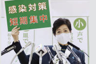 Tokyo Gov. Yuriko Koike speaks during a news conference Wednesday, Nov. 25, 2020, in Tokyo. The board reads "infection control measures, Short and intensive." (Kyodo News via AP)