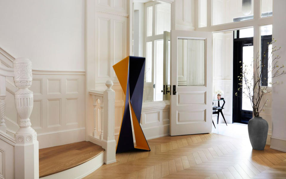 White entryway with half-panelled walls and an orange and blue sculpture