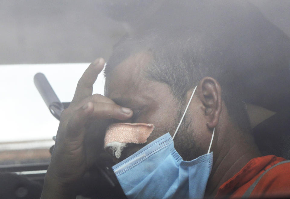 A man rescued by the Indian navy from a barge that sank in the Arabian sea and brought by Indian naval ship INS Kochi reacts as he sits inside a vehicle in Mumbai, India, Wednesday, May 19, 2021. The barge carrying personnel deployed for offshore drilling sank off Mumbai as a deadly cyclone blew ashore this week. (AP Photo/Rajanish Kakade)