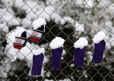 Socks that belong to stranded refugee children are covered by snow as they hang on a fence during a snowstorm at a refugee camp north of Athens, Greece January 10, 2017.REUTERS/Yannis Behrakis