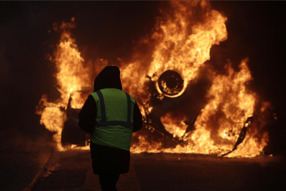 A demonstrator watches a burning car near the Champs-Elysees avenue during a demonstration Saturday, Dec.1, 2018 in Paris. French authorities have deployed thousands of police on Paris' Champs-Elysees avenue to try to contain protests by people angry over rising taxes and Emmanuel Macron's presidency. (AP Photo/Kamil Zihnioglu)