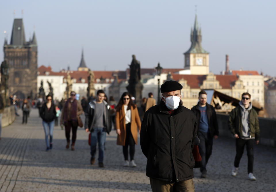 A man wearing a face mask walks across the medieval Charles Bridge in Prague, Czech Republic, Thursday, Feb. 25, 2021. The Czech government is barring the citizens and residents from travelling to the countries hit by highly contagious coronavirus variants and is tightening the rules for face coverings. Starting on Thursday, the Czechs are required to wear better masks in places where large numbers gather, including stores, hospitals and public transportation. (AP Photo/Petr David Josek)