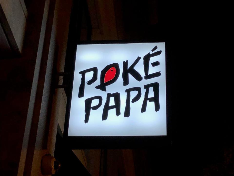 Poke Papa's lit sign with black lettering on a white background outside of the restaurant in Washington DC