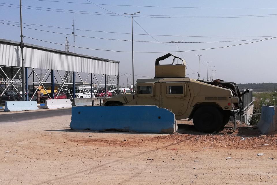 Security forces reopen a checkpoint after the explosion outside Karbala, Iraq, Saturday, Sept. 21, 2019. A bomb exploded on a minibus packed with passengers outside the Shiite holy city of Karbala Friday night, killing and wounding civilians, Iraqi security officials said. (AP Photo/Hadi Mizban)