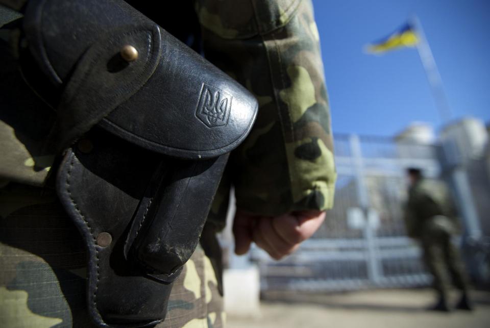 Ukrainian state emblem is seen on a gun's holster as soldiers guard naval base in the village of Novoozernoye, some 91 km west of Crimean capital Simferopol, Ukraine, on Monday, March 3, 2014. Ukraine says Russian forces controlling the strategic region of Crimea are demanding that the crew of two Ukrainian warships in Sevastopol's harbor must surrender. (AP Photo/Ivan Sekretarev)