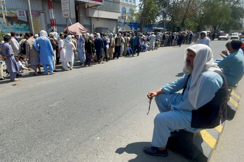 Afghans line up outside a bank to take out their money after Taliban takeover in Kabul