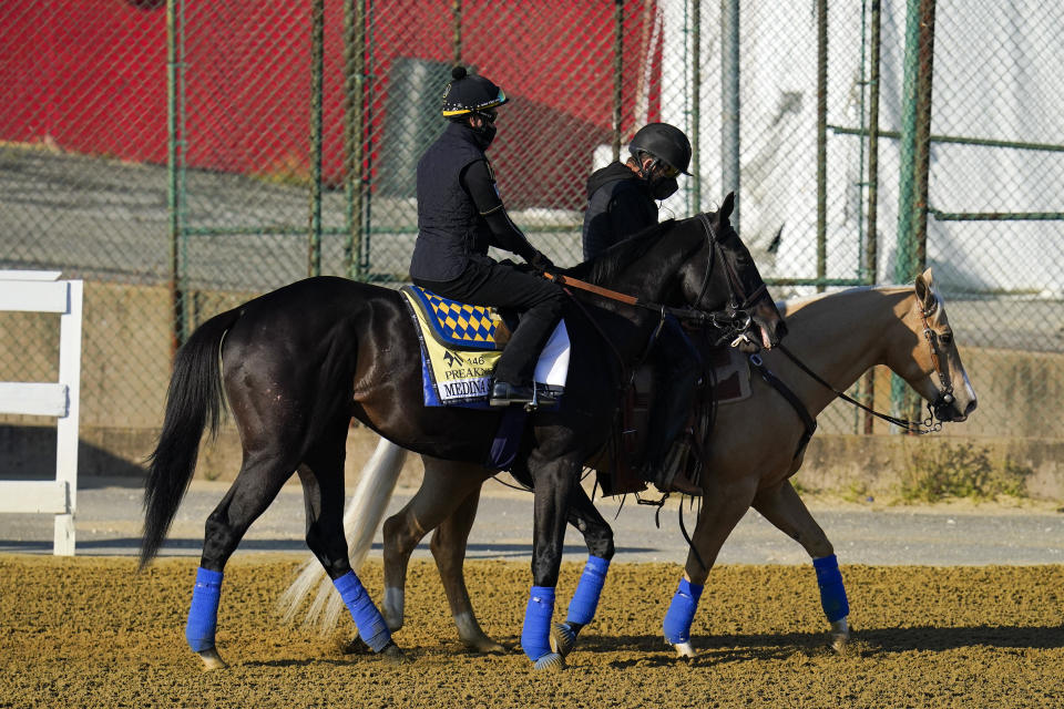 Kentucky Derby winner Medina Spirit, left, leaves the track at Pimlico Race Course after a morning exercise ahead of the Preakness Stakes horse race, Tuesday, May 11, 2021, in Baltimore. (AP Photo/Julio Cortez)