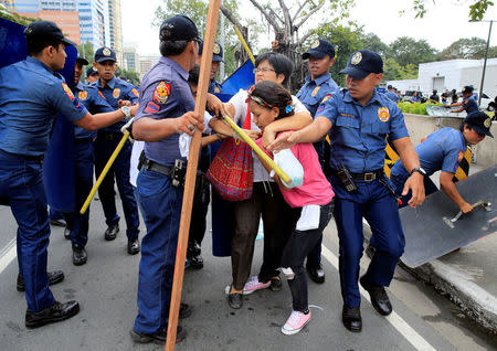 Policemen try to detain a protester after a violent dispersal of various activist and Indigenous People's (IP) groups protesting against the continuing presence of U.S. troops in the Philippines in front of the U.S. Embassy in metro Manila, Philippines October 19, 2016. REUTERS/Romeo Ranoco