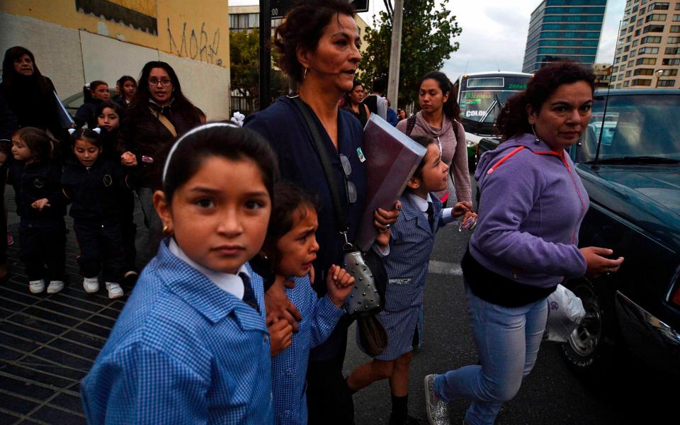 Women and schoolchildren evacuate a building during a 7.1 magnitude quake in Vina del Mar, Chile on Monday - Credit: AFP