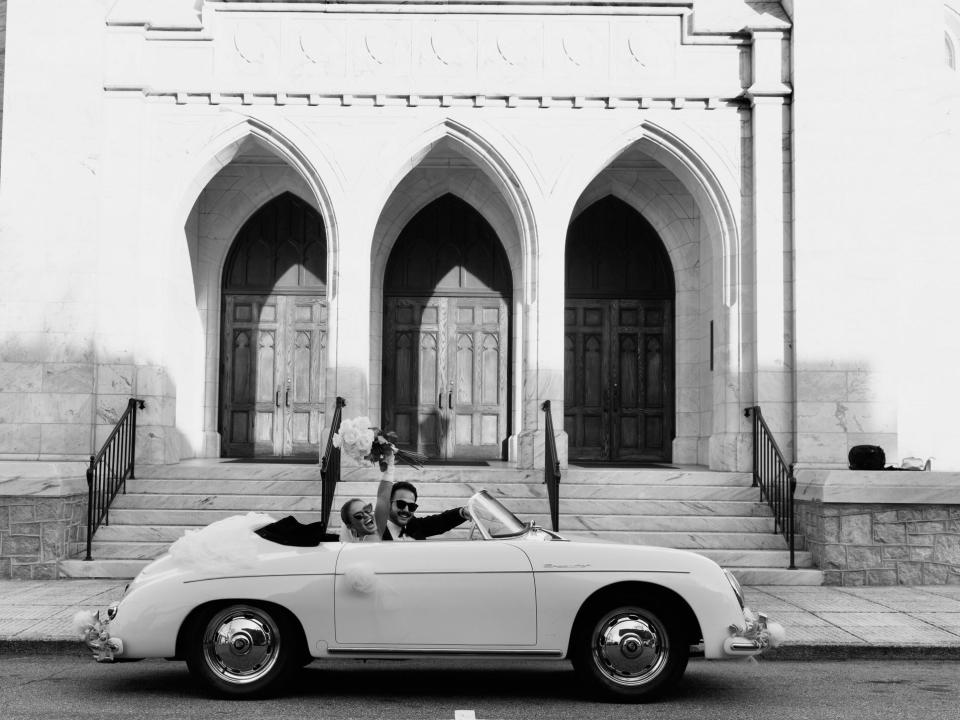 A black and white photo of a married couple in a car.