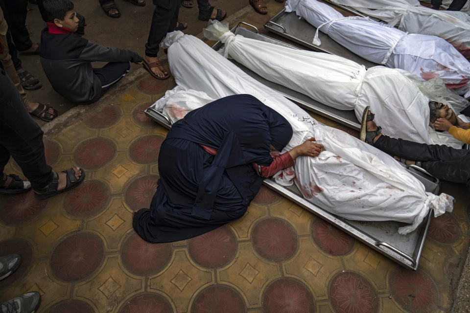 A woman mourns the covered bodies of her child and her husband killed in an Israeli army bombardment of the Gaza Strip, in the hospital in Khan Younis, Tuesday Dec. 5, 2023. Associated Press photographers have captured what six months of devastating war have brought for Israel and for Palestinians. At its six-month mark, it is not clear what direction the war will now take. Weeks of mediation by the U.S., Egypt and Qatar for a longer cease-fire have so far been unable to make a breakthrough. (AP Photo/Fatima Shbair)