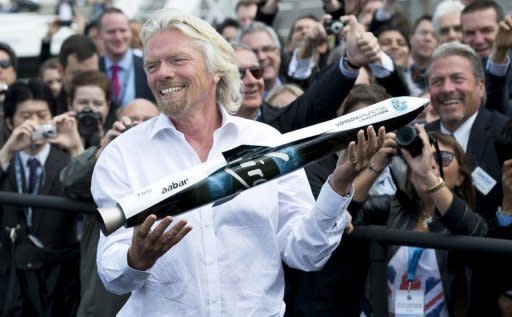 British tycoon Richard Branson poses with a model of Launcher One, an air-launched rocket, to the crowd during a photocall for Virgin Galactic, the world’s first commercial spaceline, at the Farnborough International Airshow in Hampshire, southern England, on Wednesday. Branson said he and his family will be the first on board his new Virgin Galactic space tourism programme