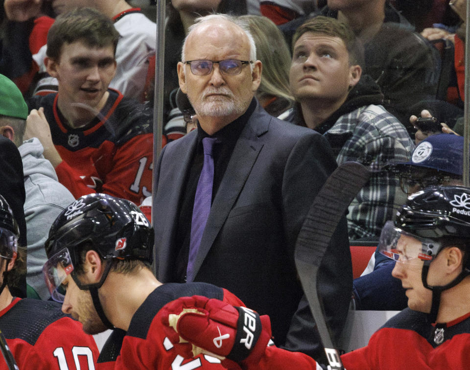 FILE - New Jersey Devils head coach Lindy Ruff, center, looks toward the ice during the third period of an NHL hockey game against the Carolina Hurricanes in Raleigh, N.C., Feb. 10, 2024. The Devils have fired Ruff. Assistant Travis Green has been named as the interim replacement. General manager Tom Fitzgerald made the stunning move with less than 30 games left in the NHL season. (AP Photo/Ben McKeown, File)