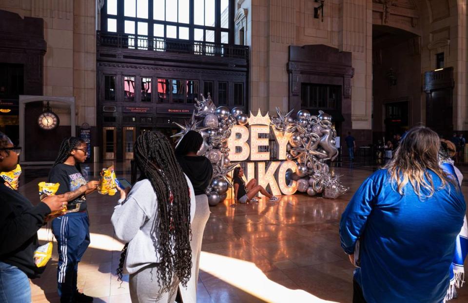Martesha Austin, center, sits down while she poses for a photo in front of the Beyoncé sign Friday at Union Station.