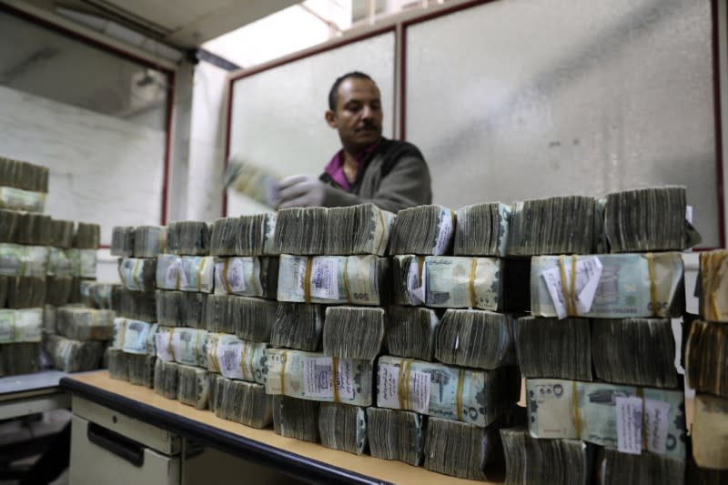 Employee counts newly issued bundles of Yemeni Riyal at the Central Bank of Yemen in Sanaa