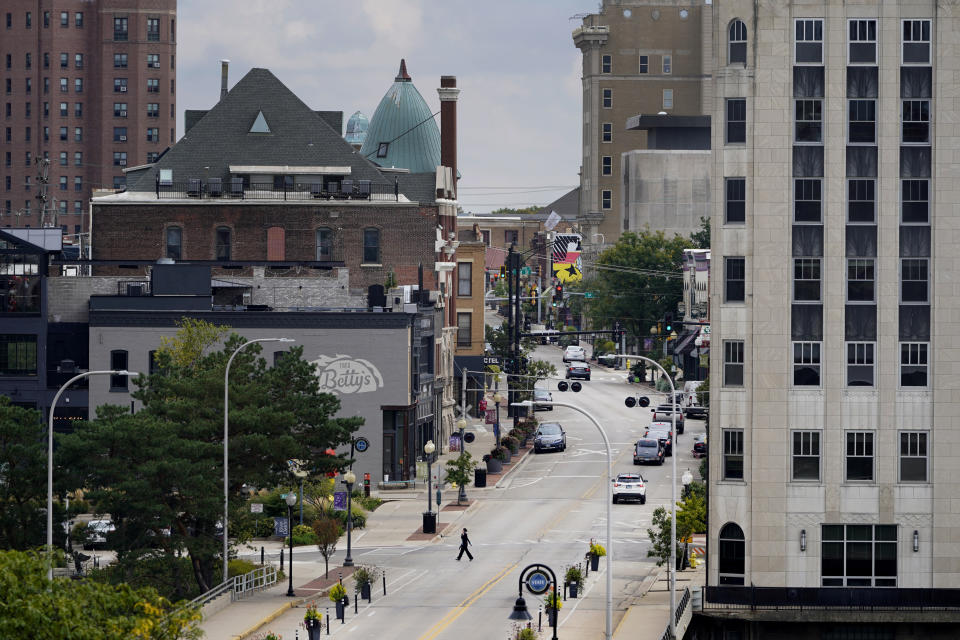 A person walks across State Street in downtown Rockford, Ill., Monday, Sept. 20, 2021. The money flowing to cities and states from the American Rescue Plan is so substantial and can be used for so many purposes that in Rockford, that means a new approach to addressing violent crime in a city that has struggled with violence for years, especially during the pandemic. (AP Photo/Charles Rex Arbogast)