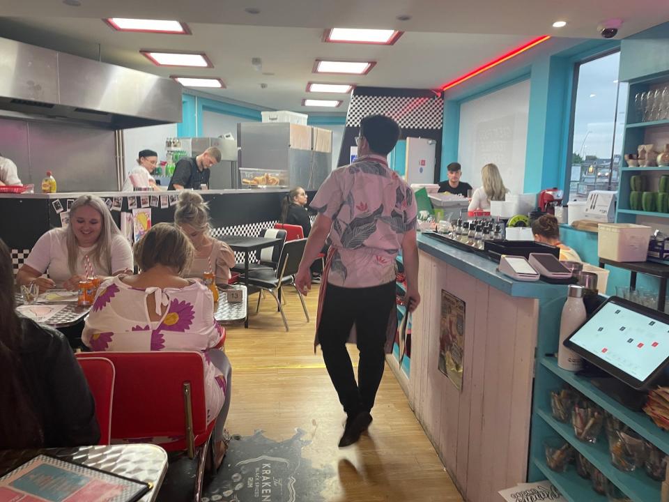 A view towards the kitchen at Karen's Diner, with the host walking guests to a table