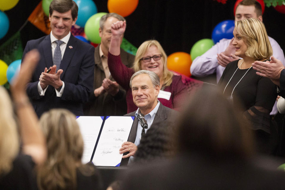 Gov. Greg Abbott, center, displays his signature on House Bill 119 also known as "Daniel's Law" into law at the Midland Chapter of the Republican National Hispanic Assembly's Reagan Lunch at the Bush Convention Center Friday, Nov. 5, 2021, in Midland, Texas. "Daniel's Law" prohibits organ transplant recipient discrimination on the basis of certain disabilities. House Bill 191 was authored by State Rep. Brooks Landgraf. (Jacob Ford/Odessa American via AP)