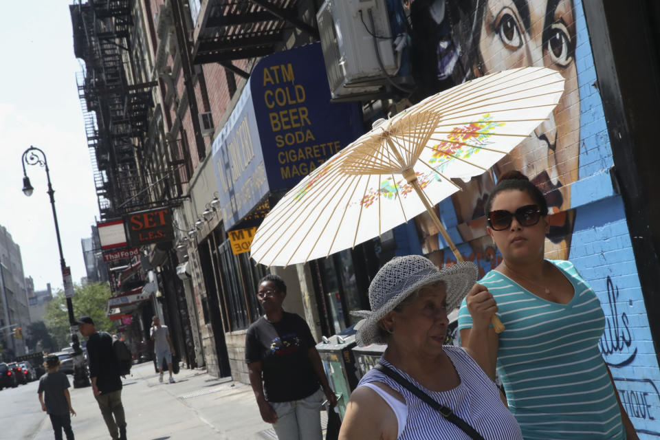 Women use a paper parasol to shield themselves from the sun, Wednesday, Aug. 29, 2018, in New York. The National Weather Service says temperatures in the 90s combined with high humidity are pushing the heat index past 100. (AP Photo/Mary Altaffer)