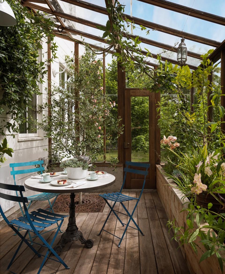 The charming greenhouse has passion vine, star jasmine, and a zellige tabletop with vintage cast-iron base.