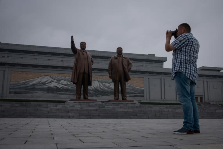 A tourist takes a photo of statues of late North Korean leaders Kim Il-Sung (L) and Kim Jong-Il (R), on Mansu hill