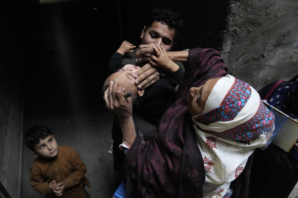 A health worker administers a polio vaccine to at a neighborhood of Lahore, Pakistan, Monday, Nov. 28, 2022. Pakistani authorities launched a new nationwide anti-polio drive on Monday amid a spike in new cases among children, health officials said. It is the sixth such campaign this year and will last for five days, aiming to inoculate children under the age of 5 in high-risk areas. (AP Photo/K.M. Chaudary)