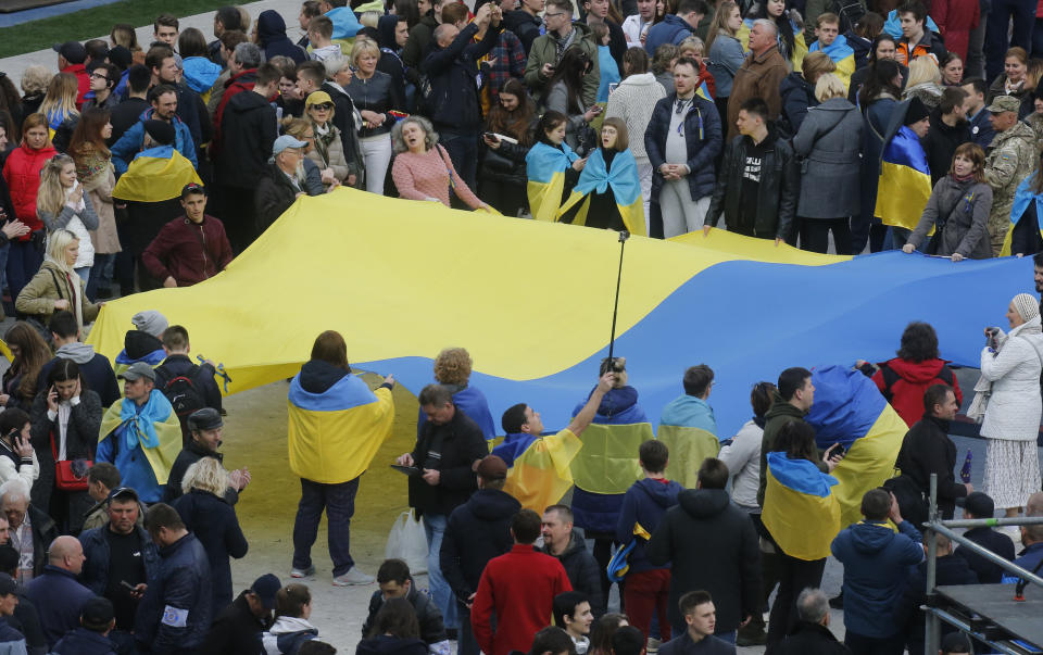 People hold Ukrainian national flag at the Olympic stadium prior debates between two candidates in the weekend presidential run-off in Kiev, Ukraine, Friday, April 19, 2019. Friday is the last official day of election canvassing in Ukraine as all presidential candidates and their campaigns will be barred from campaigning on Saturday, the day before the vote. (AP Photo/Efrem Lukatsky)