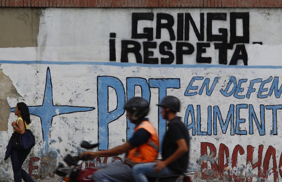 A motorcyclist rides past a wall spray painted with a demand that reads in Spanish: "Respect us Yankee", in Caracas, Venezuela, Tuesday, Aug. 6, 2019. Donald Trump signed an executive order Monday freezing Venezuelan government assets in significant escalation of tensions with Nicolas Maduro. While the order falls short of an outright trade embargo it represents the most sweeping U.S. action to remove Maduro since the Trump administration recognized Juan Guaido as Venezuela's rightful leader in January. (AP Photo/Leonardo Fernandez)