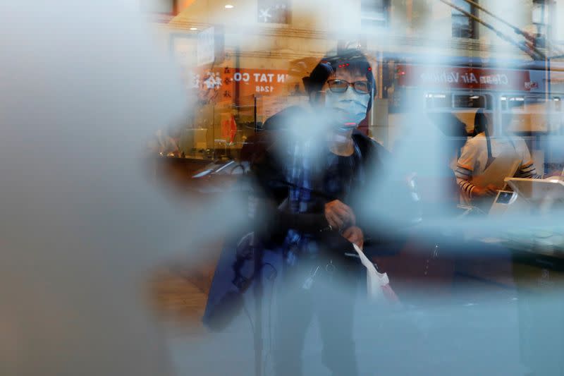 A woman wearing a face mask leaves a market in the Chinatown section of San Francisco