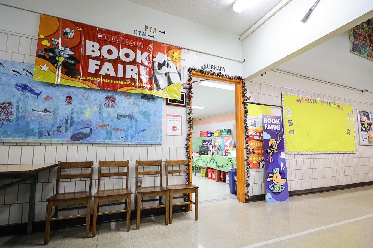 A book fair is promoted with signs in an elementary school hallway.