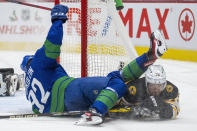 Vancouver Canucks right wing Vasily Podkolzin (92) gets tangles up with Boston Bruins defenseman Connor Clifton (75) during the second period of an NHL hockey game Wednesday, Dec. 8, 2021 in Vancouver, British, Columbia. (Jonathan Hayward/The Canadian Press via AP)