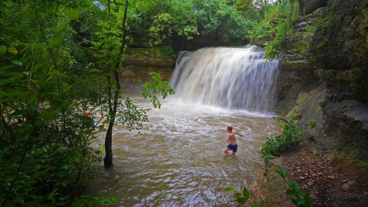 Two young men (one is obscured by the trees at left) play in Millikin Falls at Quarry Trails Metro Park. With heavy rains falling this weekend, the normally pleasant creek was roaring Sunday afternoon. A few minutes after this picture was taken, a park ranger kindly requested the boys stay away from the actual waterfall.