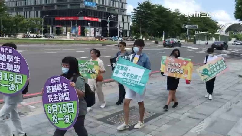 學生團體在街頭拿著看板，呼籲大家回高雄投票。