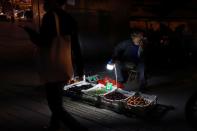 Street vendor waits for customers at his fruits stall near an exit of a subway station in Beijing