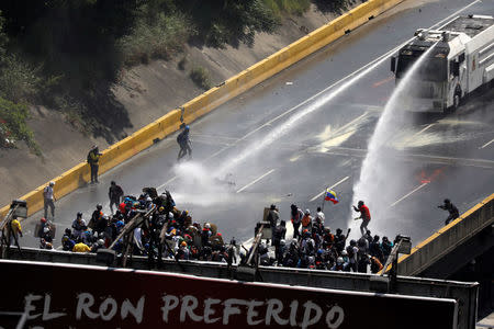 Riot security forces release jets of water from their water cannon on demonstrators during riots at a march to the state Ombudsman's office in Caracas, Venezuela May 29, 2017. The banner reads "The favorite Ron". REUTERS/Carlos Garcia Rawlins