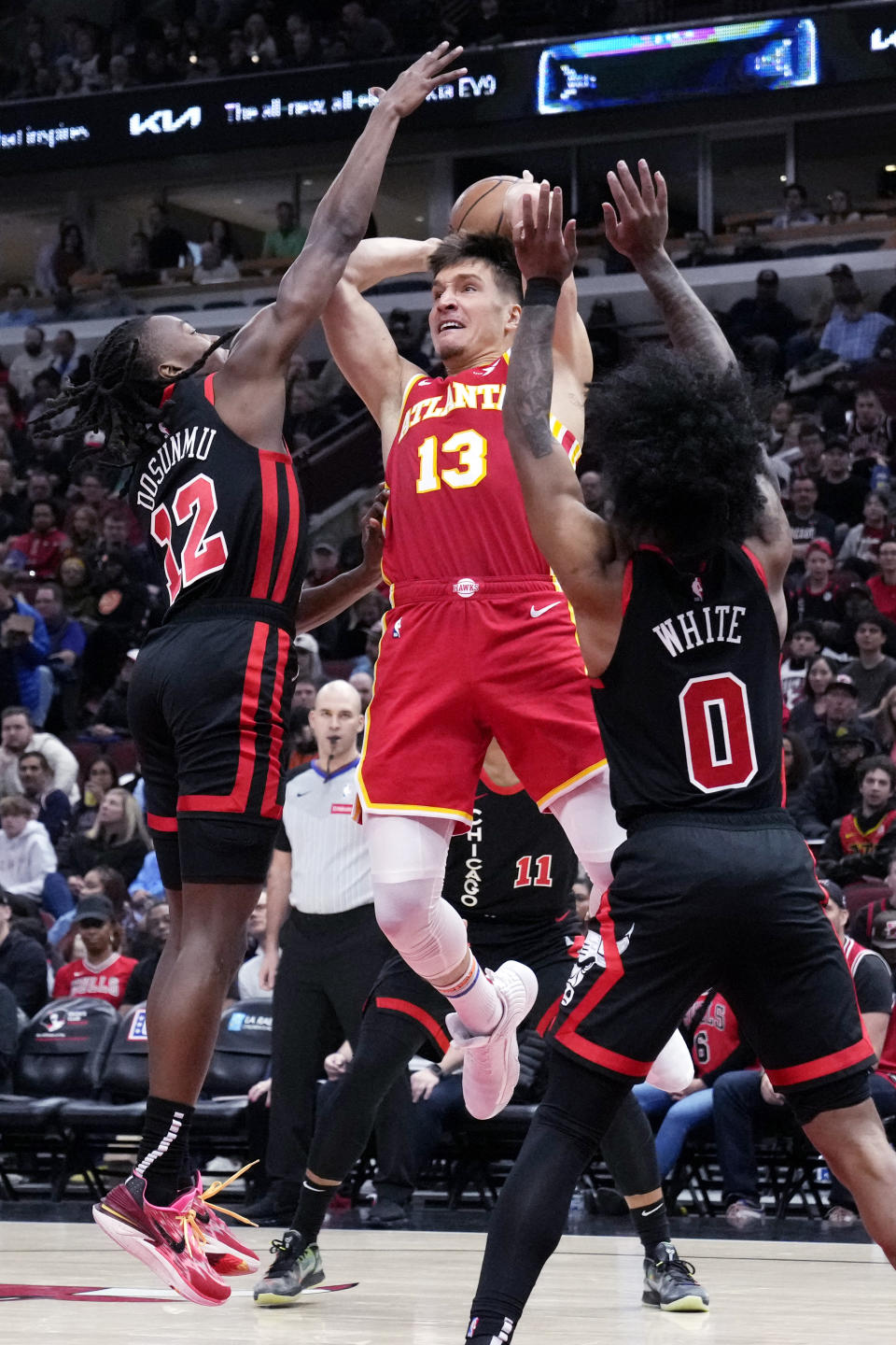 Atlanta Hawks guard Bogdan Bogdanovic, center, looks to pass as Chicago Bulls guard Ayo Dosunmu, left, and guard Coby White guard during the first half of an NBA basketball game in Chicago, Monday, April 1, 2024. (AP Photo/Nam Y. Huh)