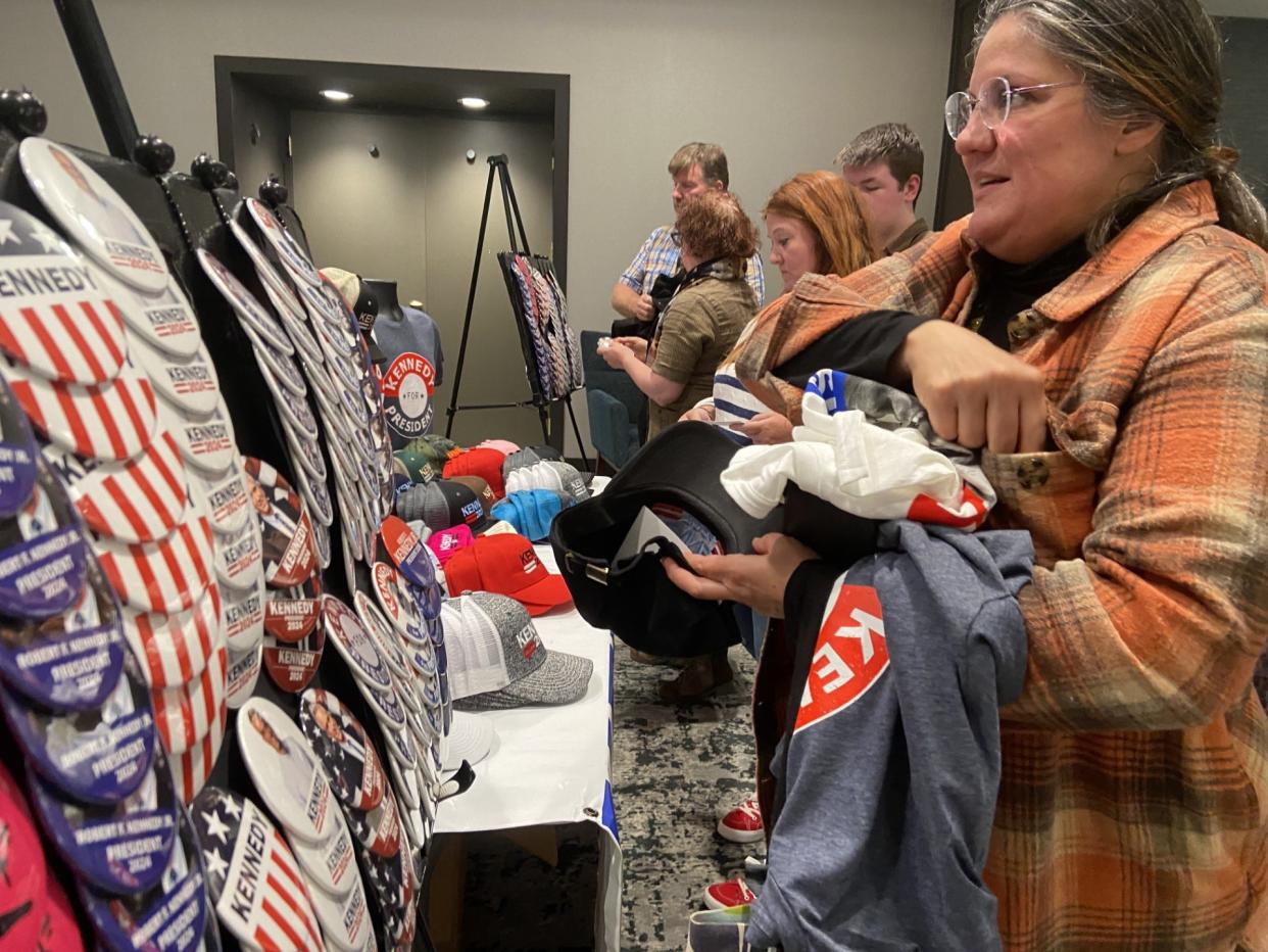 Autumn Sousanis, 54 of Lathrup Village, picks up Robert F. Kennedy swag and places some of her new buttons into a new ball cap to carry them at an event for Kennedy at the Doubletree Hilton in downtown Lansing on Oct. 7, 2023.