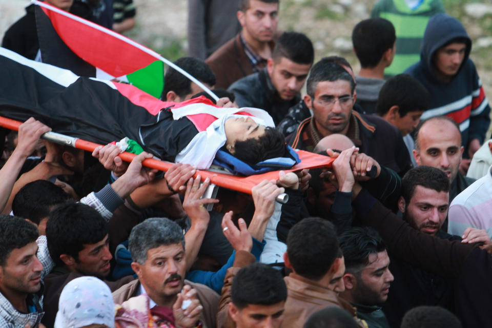 Palestinians carry the body of teenager Yussef Shawamreh during his funeral in the West Bank village of Deir al-Asa, south of Hebron, Wednesday, March 19, 2014. The Israeli military said soldiers have shot and killed a Palestinian who was among a group trying to break through the West Bank separation fence. (AP Photo/Nasser Shiyoukhi)