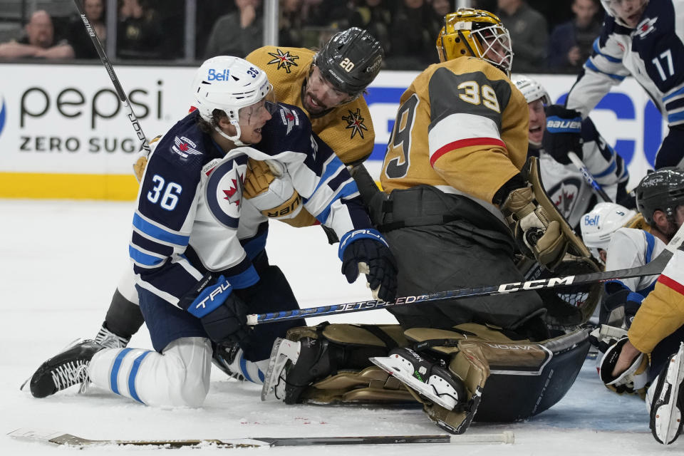 Vegas Golden Knights center Chandler Stephenson (20) helps Winnipeg Jets center Morgan Barron (36) after Barron cut his face on a skate during the first period of Game 1 of an NHL hockey Stanley Cup first-round playoff series Tuesday, April 18, 2023, in Las Vegas. (AP Photo/John Locher)