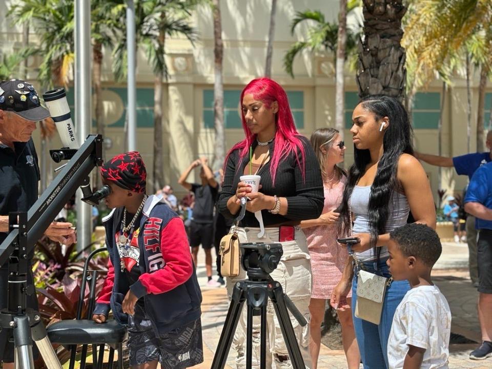 People gather at City Hall in downtown West Palm Beach to view the 2024 solar eclipse.