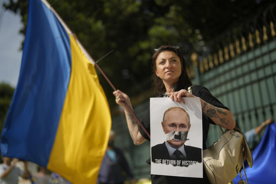 Ukrainians who live in Brazil protest outside Russia's consulate on the one-year anniversary of Russia's invasion of Ukraine, in Sao Paulo, Brazil, Friday, Feb. 24, 2023. The sign shows Russian President Vladimir Putin, alluding him to Germany's late dictator Adolf Hitler. (AP Photo/Andre Penner)
