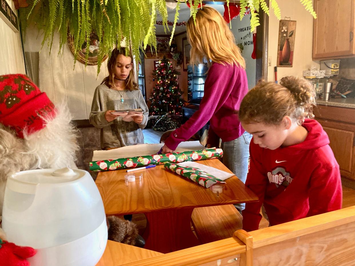Frieda Hardy's granddaughters Kaiden, Isabella and Teagan wrap toys for the Stuff a Bus toy drive. Community members are asked to bring toys to Secrest Auditorium on Dec. 4 to raise the spirits of Muskingum County's underprivileged and displaced youth.