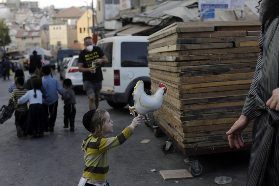 An ultra-Orthodox Jewish child plays with a ballon in the shape of a chicken during the Kaparot ritual in Jerusalem, Wednesday, Sept. 23, 2020. Observant Jews believe the ritual transfers one's sins from the past year into the chicken, and is performed before the Day of Atonement, Yom Kippur, the holiest day in the Jewish year, which takes place this year during a nationwide three-week lockdown to curb the spread of the coronavirus. (AP Photo/Maya Alleruzzo)