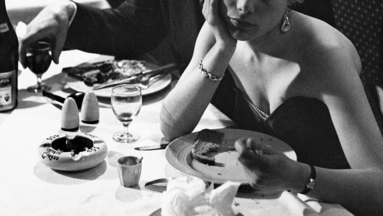 a woman and a man sitting at a table eating food